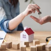 close up woman s hand giving house key man wooden table