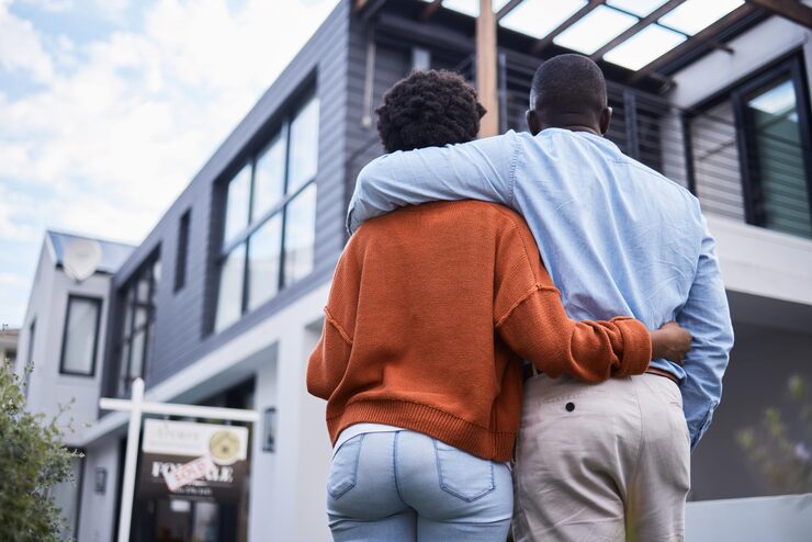 love hugging back couple by their new home property real estate standing together relocation romance african man woman homeowners embracing by their modern house